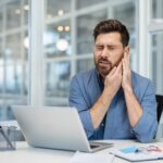 Man sitting at desk with ear ache
