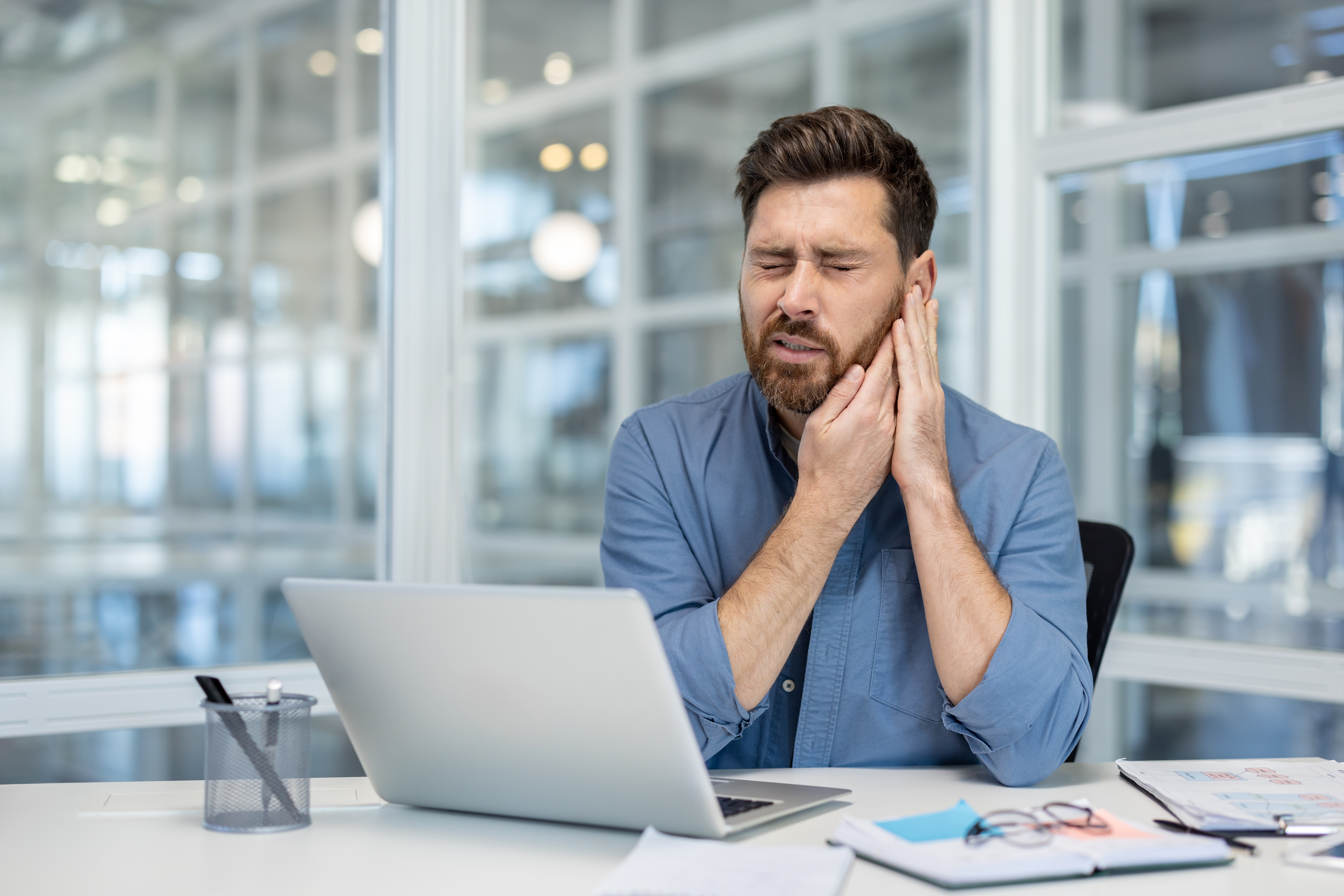 Man sitting at desk with ear ache